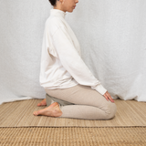 Méditation assise sur un tapis de yoga en soie brute et jute déplié sur un sol intérieur, utilisé comme tapis de méditation