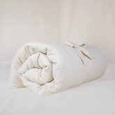 Futon écru en tissu nid d’abeille, déroulé, garni de kapok naturel, confectionné à la main au Maroc par Atelier Cocon, idéal pour la méditation, le yoga restauratif et la relaxation à la maison