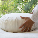Mains installant délicatement un coussin de méditation traditionnel en lin 