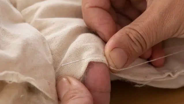 mains qui coud un tissu en toile de coton rembourré au kapok naturel 