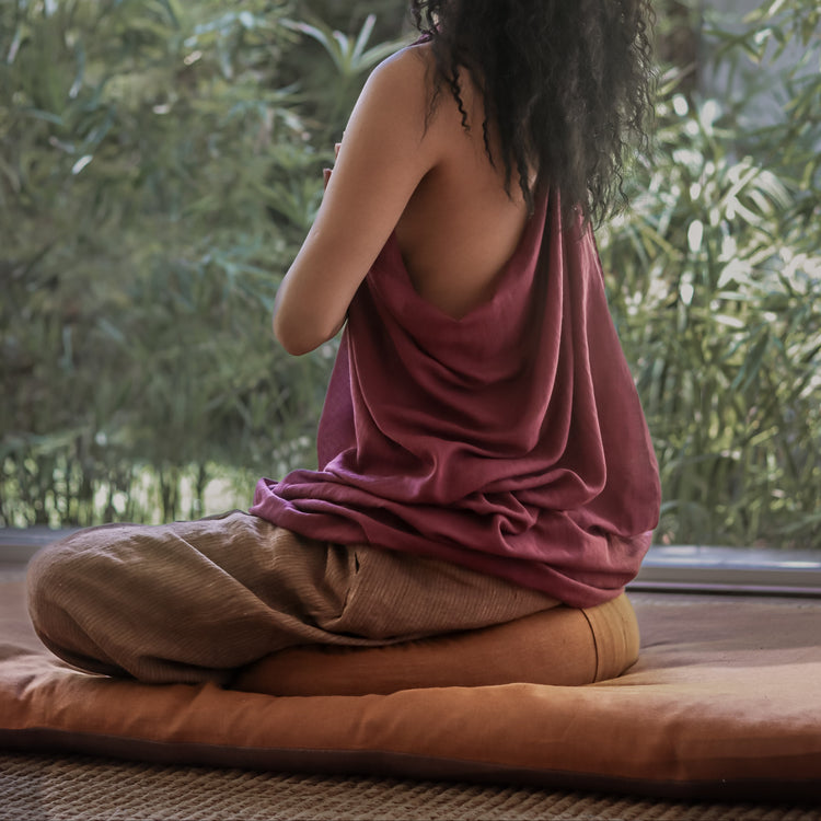 Femme assise en méditation sur Terracota Zafu Demi Lune en Lin et Kapok