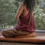 Femme assise en méditation sur Terracota Zafu Demi Lune en Lin et Kapok